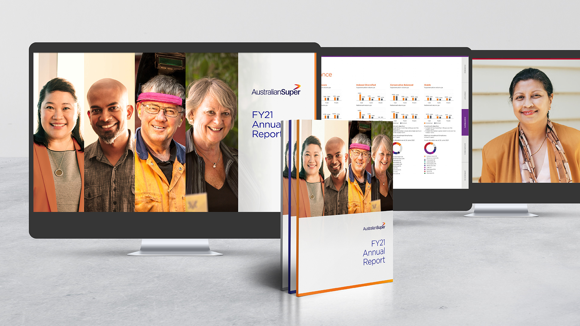 Monitors on a desktop displaying the AustralianSuperFY21 Annual Report. Three printed reports stand upright in front of the monitors.
